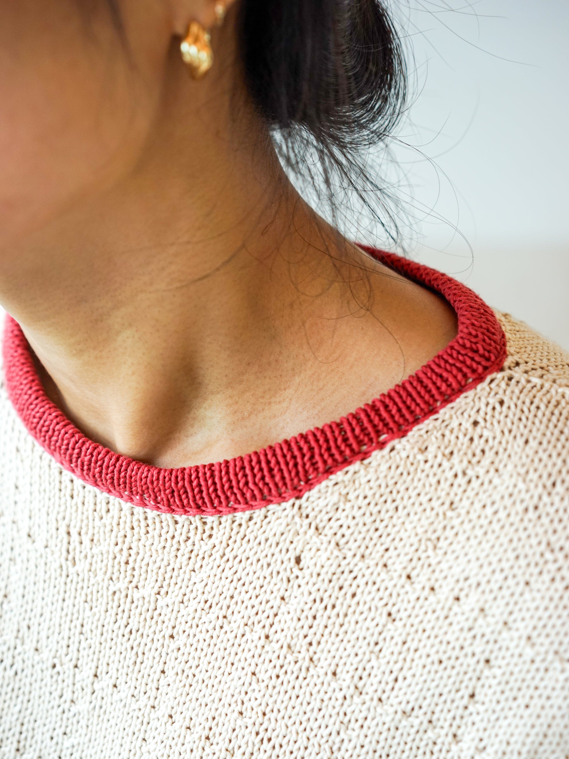 The contrast neckline trim and seed-pearl texture, close up
